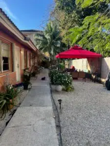 Outdoor courtyard at a Fort Lauderdale sober living home with red gazebo, patio seating, tropical plants and walkway.
