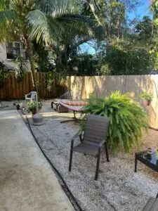 Peaceful outdoor patio area with hammock, seating, palm trees, and lush ferns at a Fort Lauderdale sober living home.